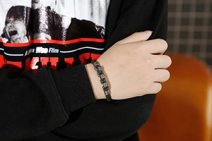 Detail of men's braided leather bracelet with matte silver interlocking chain links