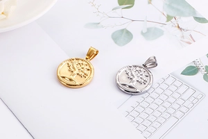 Detailed view of silver and gold tree of life pendants on minimalist white background