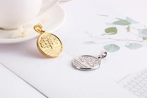 Detail view of round Tree of Life pendants in gold and silver finish on white paper