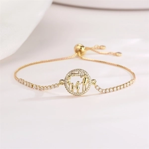 Detail of gold-tone family charm bracelet with zircon accents and adjustable drawstring cord