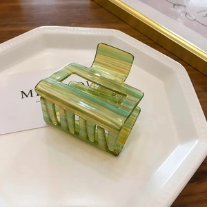 Detail showing square hollow hair claw clip with colorful marble pattern on a tray