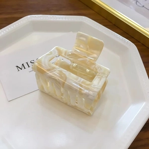 Detailed view of a cream marble textured square hair claw clip on a white decorative tray