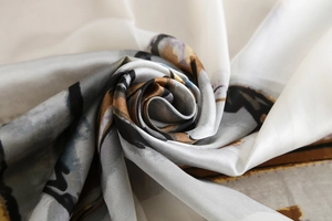Detail of soft silk satin scarf with abstract cream and brown print in a spiral fold
