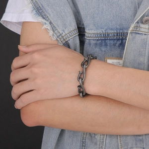 Detailed view of silver interlocking nail hook chain bracelet on a denim jacket sleeve