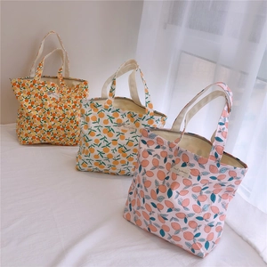 Détail de trois sacs à main en coton aux imprimés d'agrumes sur une surface en tissu blanc