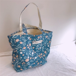Vue détaillée du sac cabas en toile à fleurs avec poignées blanches et étiquette décorative