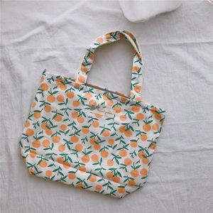 Détail du sac cabas en toile blanche avec motifs d'oranges et étiquette décorative