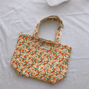 Détail du sac cabas en toile avec motifs oranges, fermeture éclair et étiquette tissu