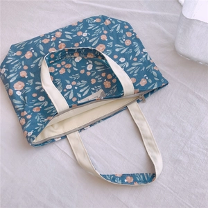 Vue détaillée du sac cabas en toile bleu marine à fleurs avec fermeture éclair et anses