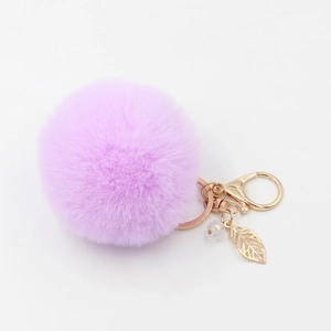 Dettaglio del portachiavi a pompon viola chiaro con foglia dorata e cristallo