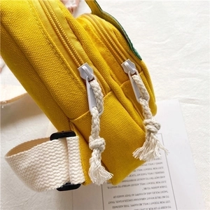 Detailed close-up of yellow canvas fabric with cotton rope zipper and woven strap