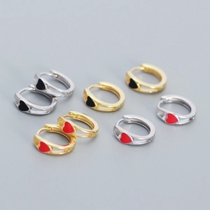 Detailed view of silver and gold heart earrings with red and black enamel inlays