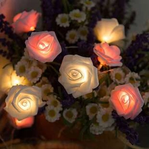 Close-up of warm glowing rose flower string lights intertwined in a romantic floral bouquet
