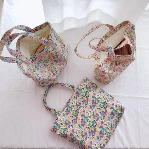 Three floral cotton tote bags in pink and blue patterns with a soft fabric background