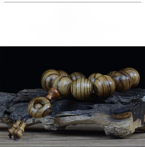 Macro detail of 108 Buddhist prayer beads on wood with a gourd pendant and natural texture