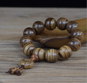 Close-up of 108 sandalwood prayer beads with natural wood grain on a wooden tray
