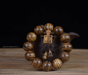 Detailed texture of 108 agarwood prayer beads with carved wooden plaque and gourds