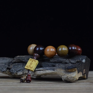 Handcrafted multi-color redwood beaded bracelet on vintage wood base with black background
