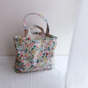 Detailed view of floral cotton tote bag with vibrant patterns on a white cloth background