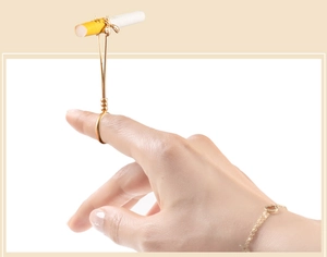 Detail of golden bee cigarette holder ring accessory shown on finger in close-up
