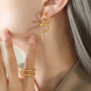 Elegant gold snake drop earrings and textured wavy rings worn by model for a trendy chic look