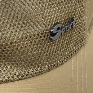 Détail macro du tissu en maille respirante et logo Sport en métal sur casquette kaki