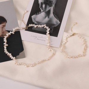 Elegant baroque pearl necklace and bracelet set with golden clasp on silk background
