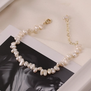 Elegant baroque pearl bracelet with gold lobster clasp on artistic frame background