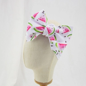 Close-up of baby headband with watermelon print and a large fabric bow on a model