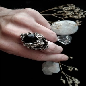 Gothic silver bat ring with oval black gemstone displayed with dried flowers