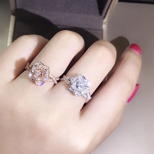 Detail of 18K rose gold and silver flower rings with micro-pave crystals on twisted bands