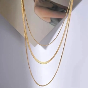 Detailed close-up of triple-layered golden snake chain necklaces with metallic luster
