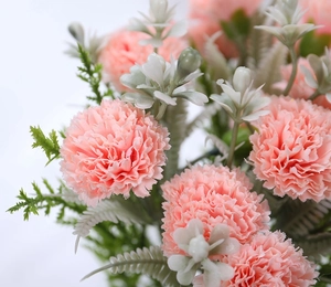 Close-up of pink artificial carnation flowers with realistic green leaves for home decor