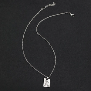 Macro shot of silver metal rectangle pendant engraved with MY DAD MY HERO text