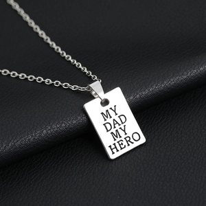 Macro view of silver rectangular pendant engraved with 'MY DAD MY HERO' on black leather