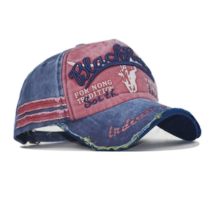 Detail of red and blue washed denim baseball cap with vintage frayed edges and embroidery