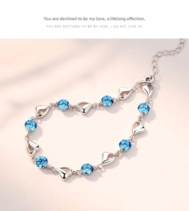 Detail of 925 sterling silver bracelet with sky blue zircon and hollow heart charms