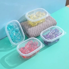 Colorful laundry beads in yellow and blue pods on a turquoise surface with a grey towel