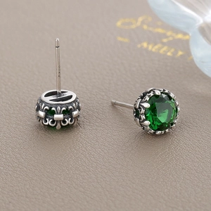 Vintage S925 sterling silver emerald zircon stud earrings on a textured leather background