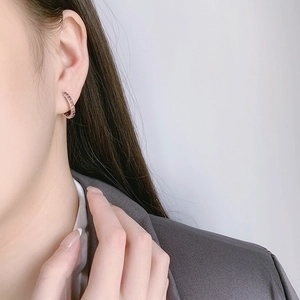 Rainbow hoop earrings with colorful zircon stones worn by a model on light background