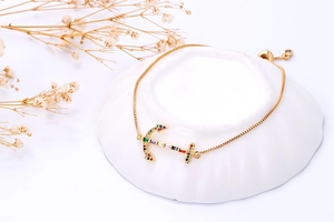 Macro-opname van gouden ankerarmband met gekleurde zirkoonstenen en een box ketting
