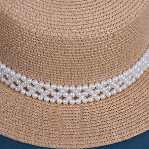 Detailansicht des Raffia-Sonnenhuts mit dreilagigem Perlenband auf dem Strohgewebe