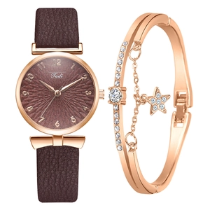 Détail d'une montre femme en or rose avec cadran brun et coffret bracelet à breloque étoile