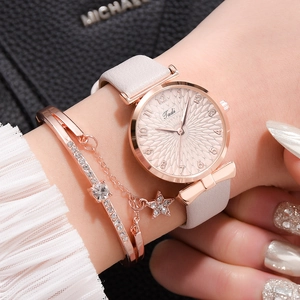 Détail d'une montre à quartz or rose avec bracelet en cuir rose et bracelet étoile