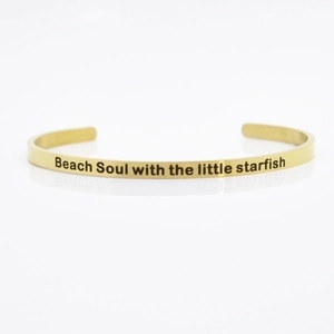 Close-up of gold 4mm stainless steel cuff bracelet engraved with Beach Soul text