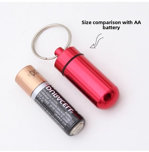 Mini red aluminum medicine container size comparison with a standard AA battery