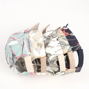Detail of four floral baseball caps with adjustable straps and vibrant summer patterns
