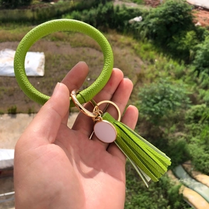 Detail of green leather keychain bracelet with tassel and rose gold metal ring