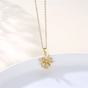 Close-up of gold flower pendant necklace with zircon stones on a white ceramic plate