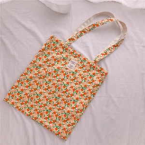 Detailed view of floral canvas tote bag with orange fruit print and fabric label patch